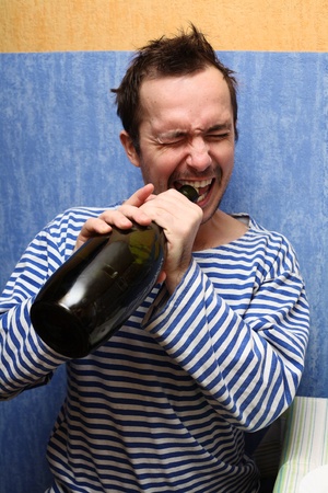 Portrait of the unshaven man, opening teeth a wine bottleの写真素材