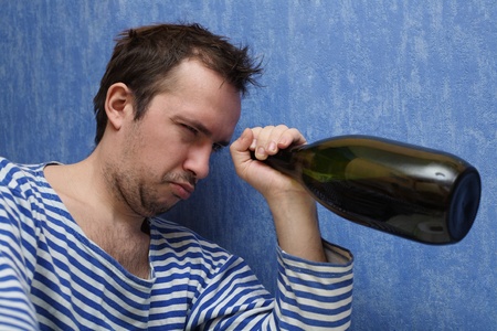 The drunkard looks in a bottle with wineの写真素材
