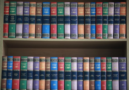 bookshelf with books neatly standing with colored coversの写真素材