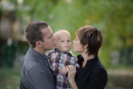 young father and mother kissing her little babyの写真素材