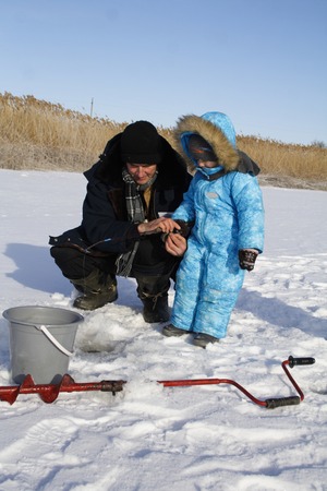 4 year old boy on winter fishing with grandpaの写真素材