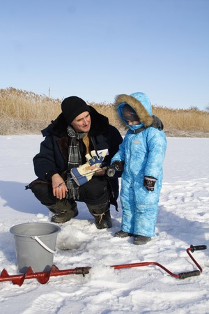4 year old boy on winter fishing with grandpaの写真素材