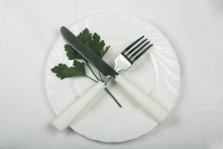 leaf parsley on a plate with knife and fork, symbolizing dietの写真素材