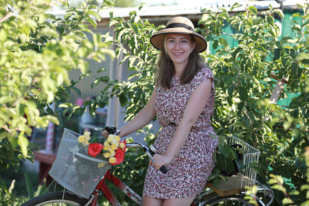 the girl in the garden with a Bicycle and a bouquet of flowersの写真素材