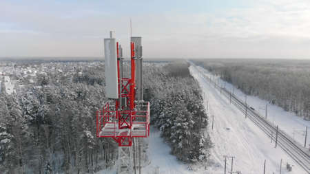 Top of 4G or 5G mobile tower in countryside next to railway on frosty, sunny winter day. Concept of...