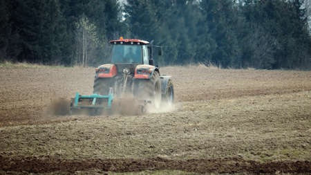 Tractor cultivates the land with a disc harrow to prepare for sowing. Agricultural machine is...