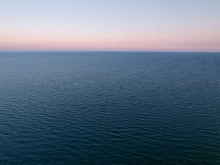 Aerial view of the endless sea surface in calm windless weather on a late summer evening.