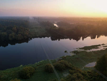 AERIAL VIEW: several high-voltage wires thrown across the river in a picturesque wooded area....