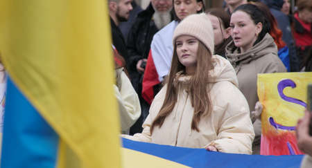 Poland, Wroclaw, April 22, 2022: Girl with a yellow-blue flag at a rally of refugees in support of...