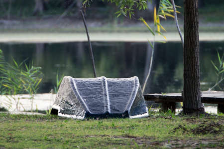 The water of the lake in the background operates tempting. Renovated bottom of the boat looking at the sky. The bow of the boat is securely tied to a tree. A boat waiting to sail.の写真素材