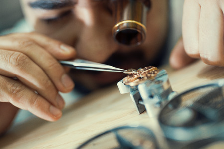 Close up portrait of a watchmaker at work.He is wearing specialist magnifying glass.