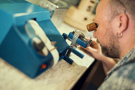 Close up portrait of a watchmaker at work. He is wearing specialist magnifying glass.の写真素材