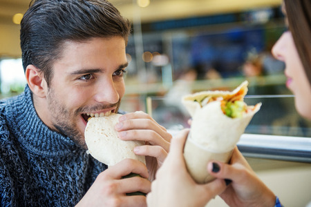 Couple looking at each other while eating fast food.They are having fun in fast food restaurant.の写真素材