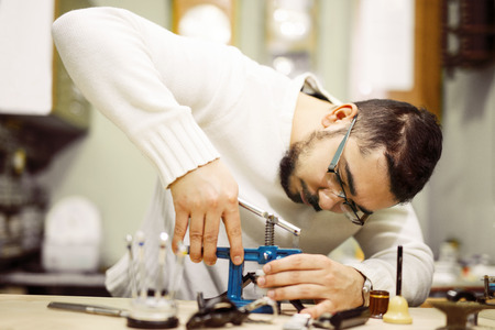 Close up portrait of a watchmaker at work.Old pocket watch being repaired by watch maker.