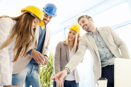 Architect looking over building plans with construction workers.Construction workers checking the architectural plans before they start the building project.の写真素材