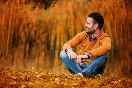 Young handsome man posing in autumn park.