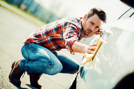 Young man cleaning his car outdoors.Man with a microfiber wipe the car polishing.の写真素材