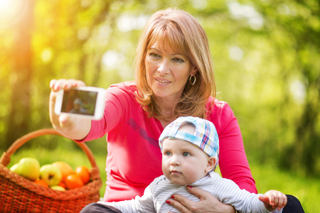 Beautiful middle aged woman and her adorable little son having a picnic in sunny park.