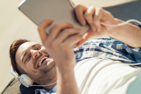 Young attractive man is smiling while wearing headphones.の写真素材