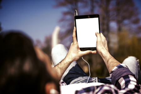 Young man listening to music on a smart phone.He is listening music on smartphone in the park.の写真素材