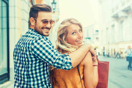 Beautiful young loving couple carrying shopping bags on shoulders and enjoying together.の写真素材