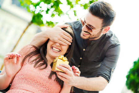 Surprise!Beautiful young woman being surprised with present.の写真素材