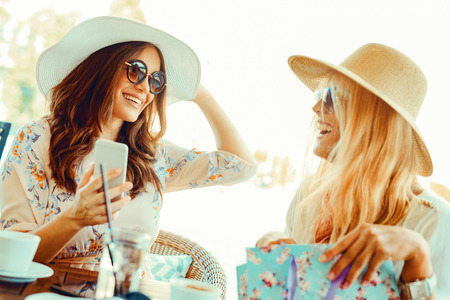 Two beautiful young women in cafe after shoppingの写真素材