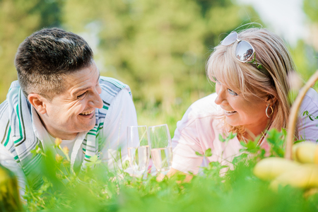 Laughing couple having picnic in countryside,holding glasses with delicious wine.の写真素材