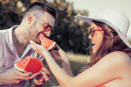 Happy couple on a picnic eating watermelon on a sunny day.の写真素材