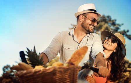 Happy young couple going for a bike ride on a sunny day in the park.の写真素材