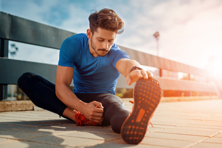 Young male jogger athlete training and doing workout outdoors in cityの写真素材