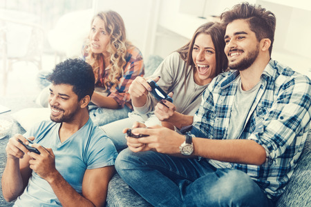 Excited friends playing video games at home and having fun.