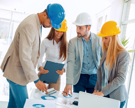 Architect looking over building plans with construction workers.Construction workers checking the architectural plans before they start the building project.の写真素材
