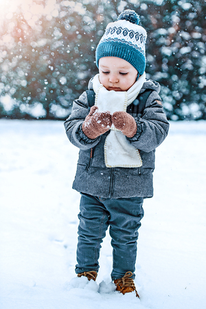Portrait of toddler boy in winter clothes with falling snowの写真素材