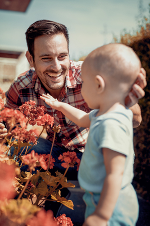 Father and son working together in the garden.Little boy helping his father to plant flowers.の写真素材