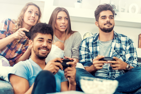 Young friends playing video games at home.