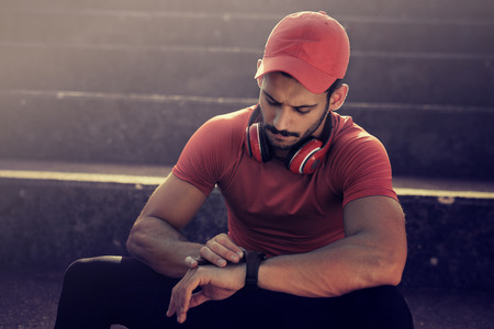 Fitness man checking performance after training.Runner training and checking stopwatch.の写真素材