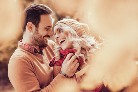 Happy young couple hugging and laughing outdoors.の写真素材