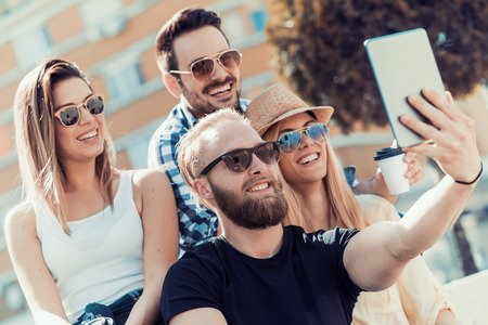 Friendship, summer,technology and people concept - smiling friends making selfie outdoors.の写真素材