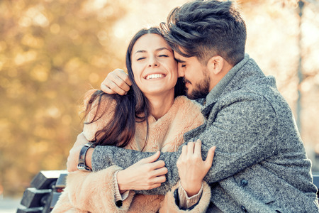Happy young couple hugging and laughing outdoors.