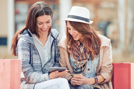 Friends having fun with tablet after shopping.の写真素材