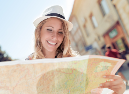 Happy young woman using a city map for location in the town.の写真素材