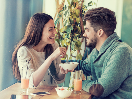 Happy young couple having breakfast in cafe,enjoying together.の写真素材