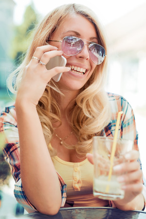Portrait of a beautiful smiling woman using a mobile phone outdoors.の写真素材