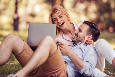 Couple using laptop in city park,having fun together.の写真素材