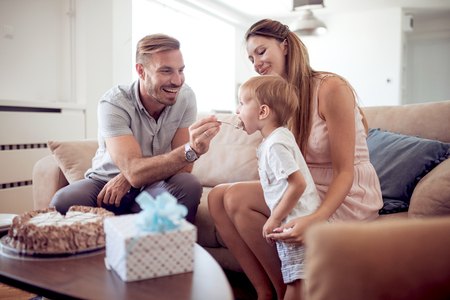 Celebration,family,holidays and birthday concept-happy family with cake-dad feeds his son with birthday cake.の写真素材