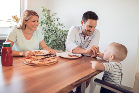 Family lunch.Father,mother and son eating a big pizza.Cooking classes concept.の写真素材