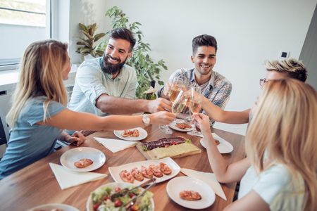Friends meeting.Group of happy people with glasses,toast,talking and eating healthy meals at party dinner at home.の写真素材