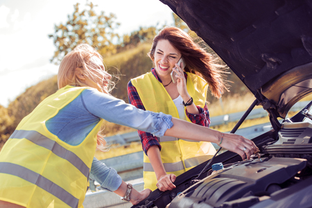 Portrait of a young girlfriends having some car trouble on a sunny day.の写真素材