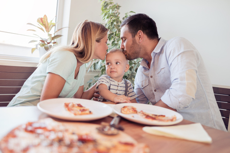 Family lunch.Father,mother and son eating a big pizza.Cooking classes concept.の写真素材